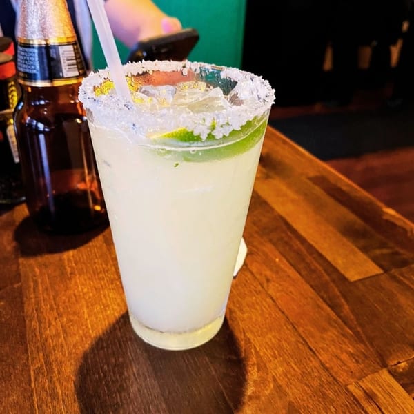 A Margarita's Cocina Mexicana margarita with a salted rim and lime, next to a beer bottle.