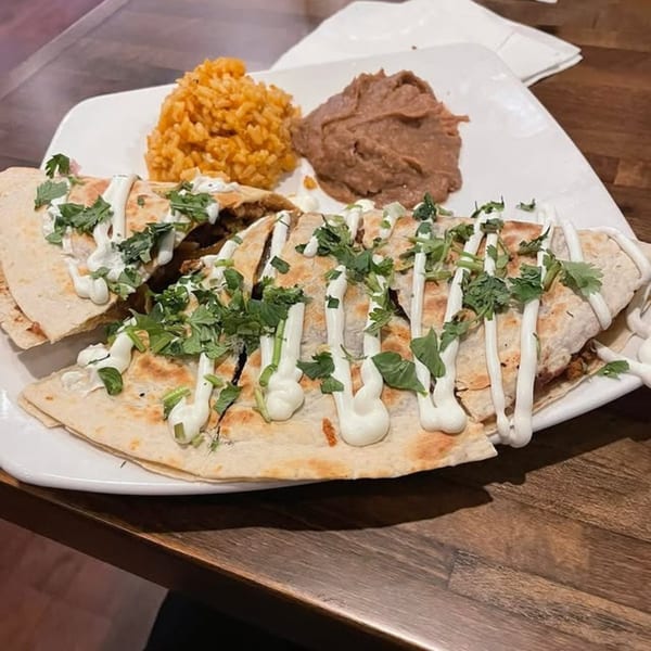 Margarita's Cocina Mexicana quesadilla with rice, refried beans, sour cream, and cilantro on a white plate.