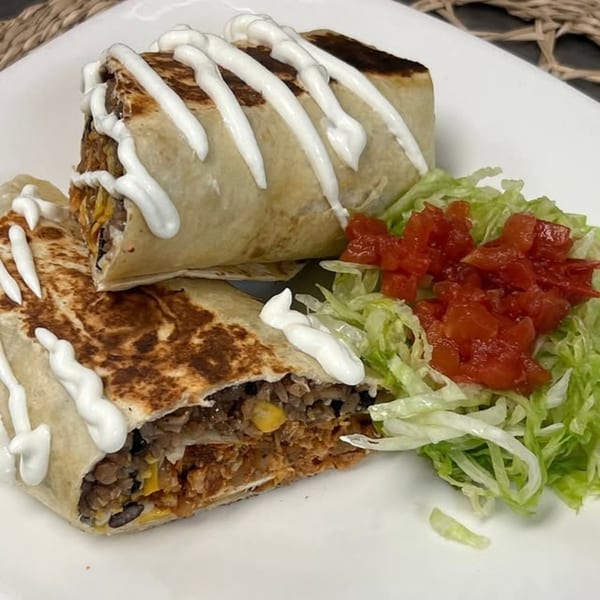 Two Margarita's Cocina Mexicana burritos topped with sour cream, served with shredded lettuce and diced tomatoes.